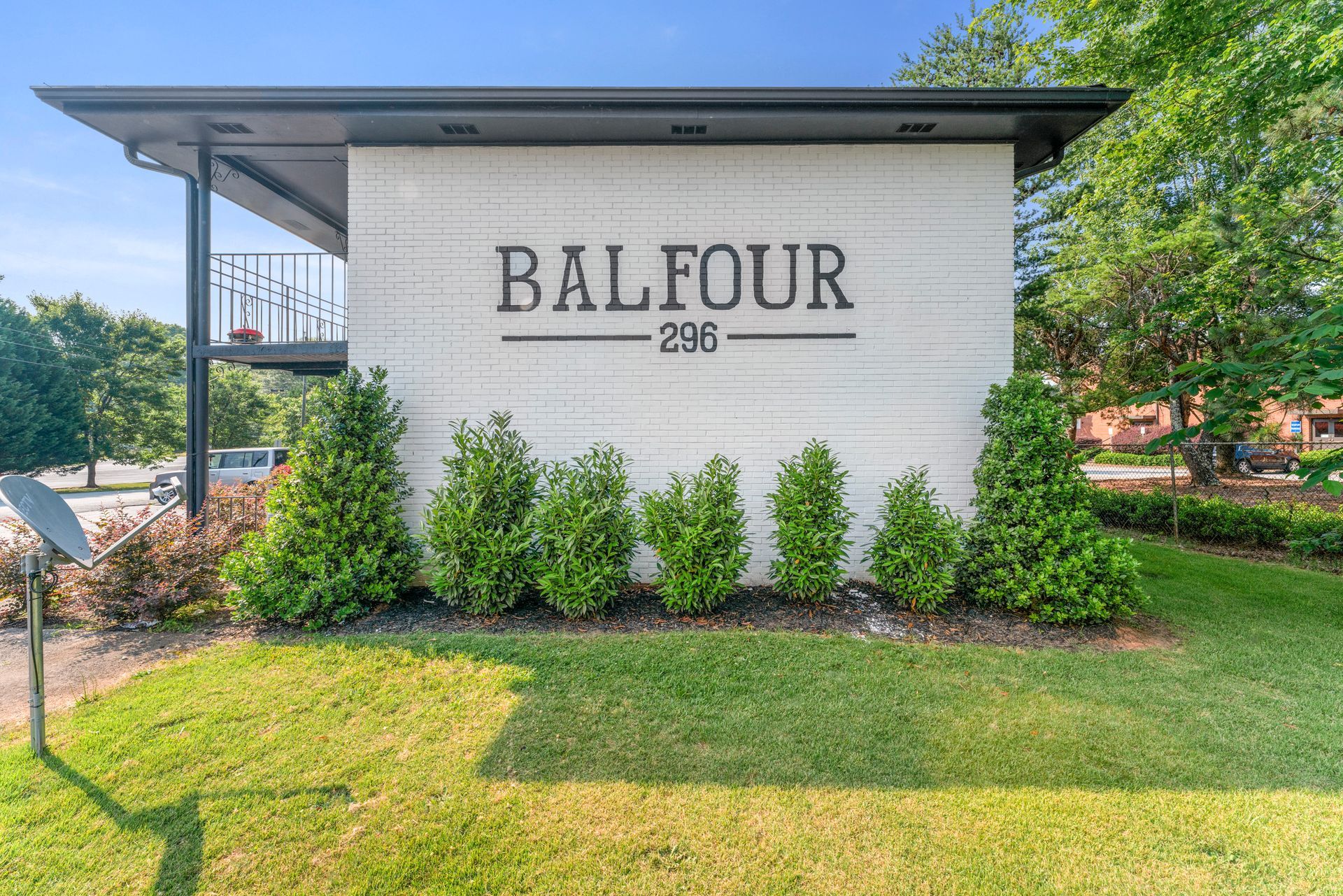 Balfour apartment building sign on a white brick wall, with landscaping and green lawn in front