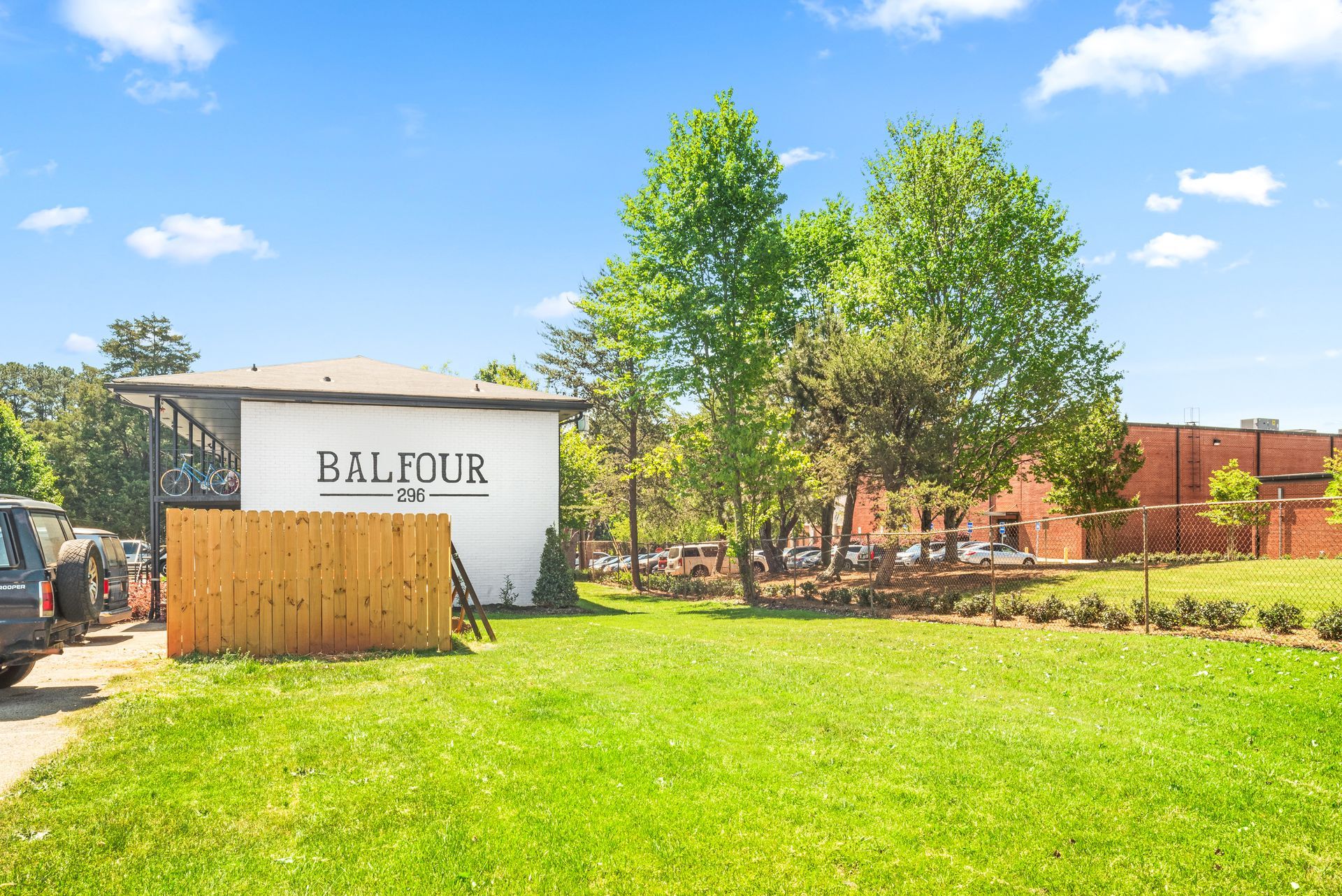 BALI CUA sign on a white building beside a green lawn and trees under a blue sky