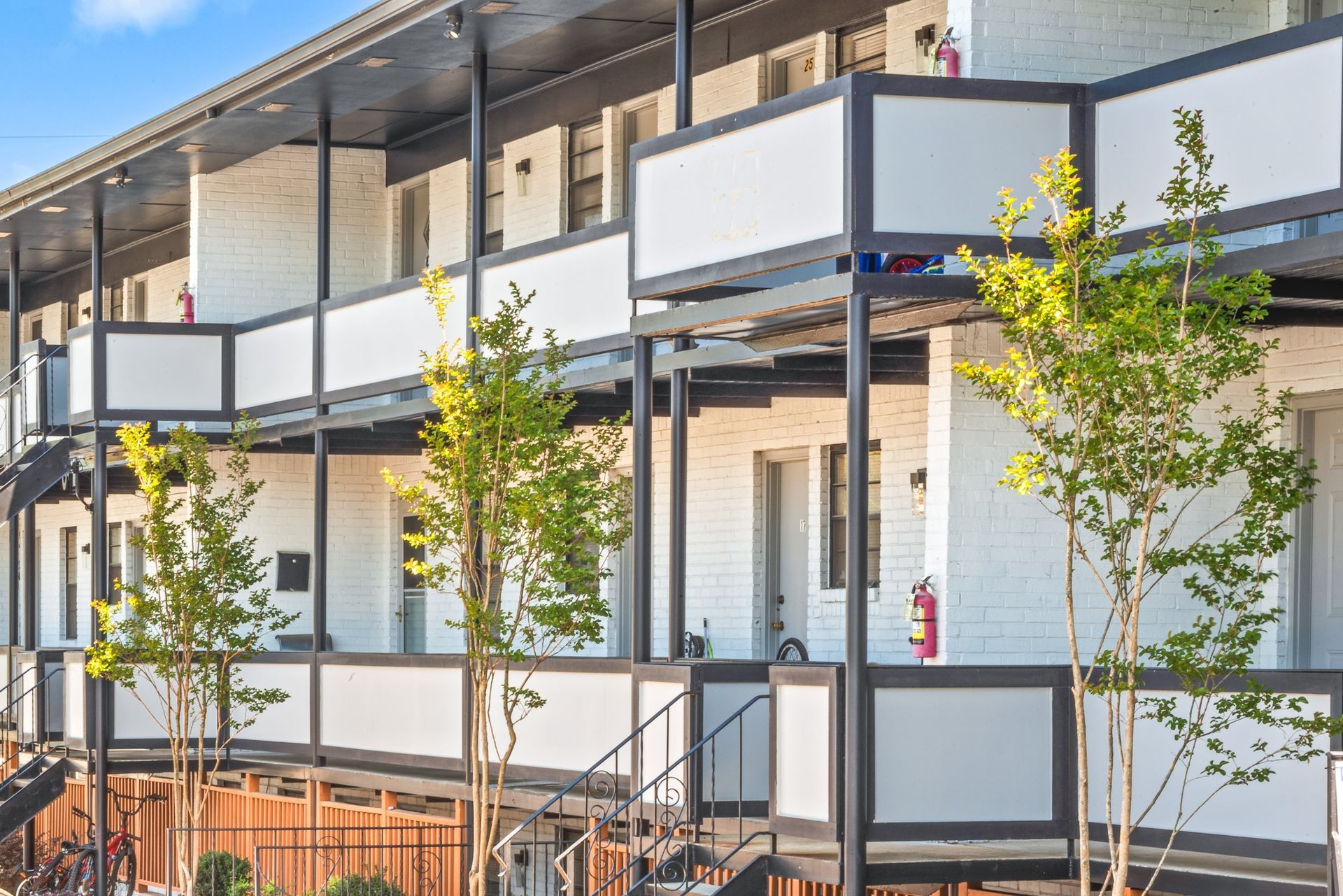 Modern apartment balconies with white and gray railings and young trees in front