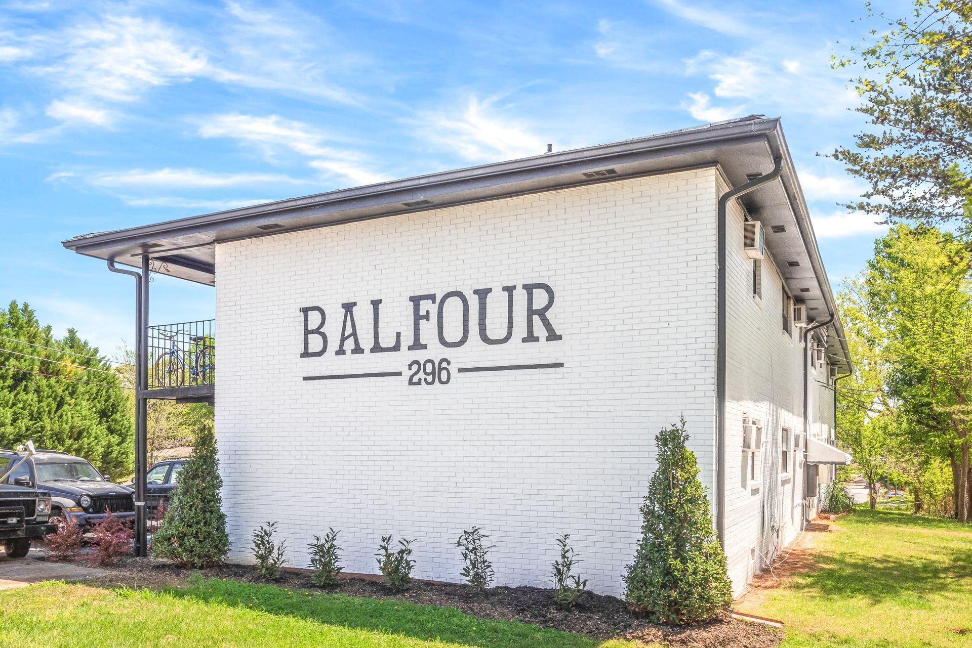 White brick building with “BALFOUR 206” painted on the side, set on a grassy lot under a blue sky.