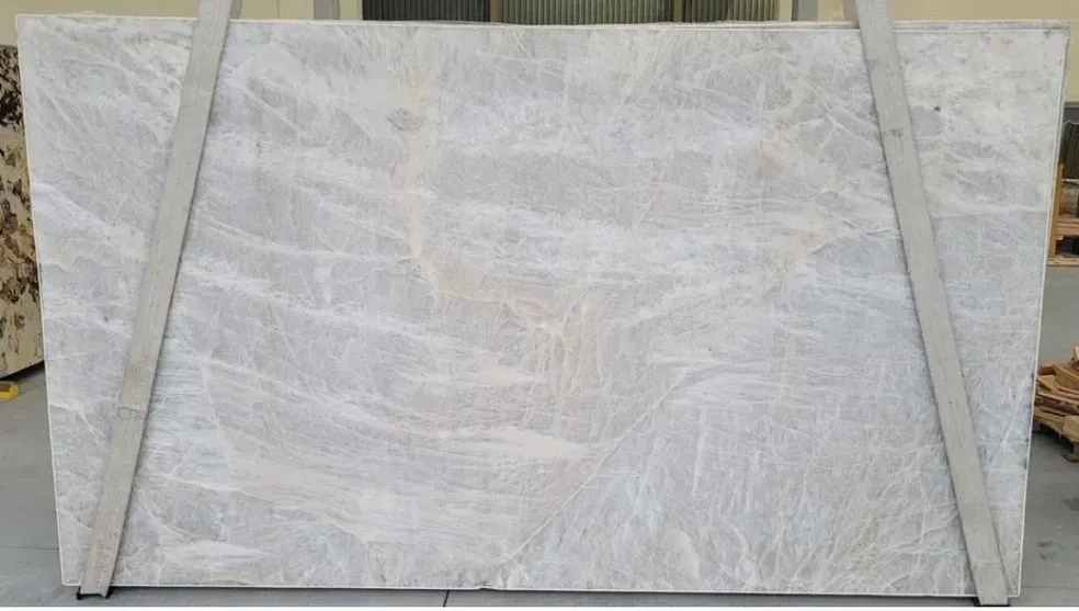 A large white marble slab is sitting on top of a cement floor.