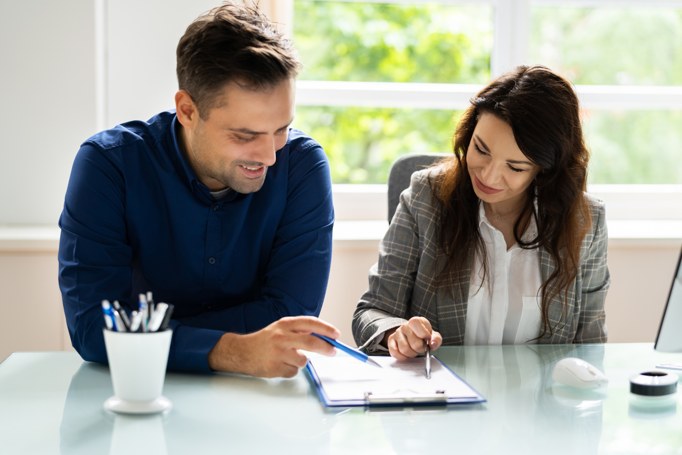 Man and woman reviewing documents together at a desk, both smiling, indoors.