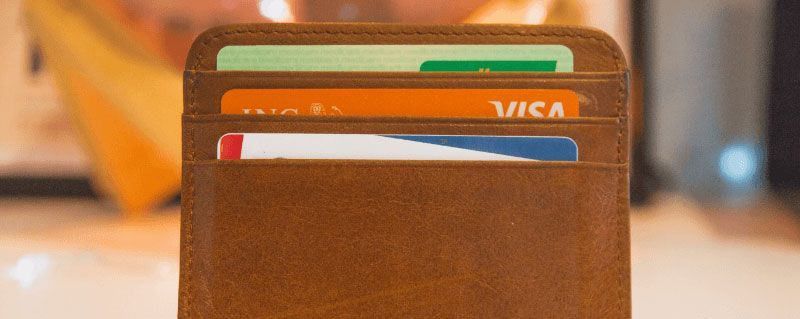 Close-up of a brown leather wallet with three credit cards visible.
