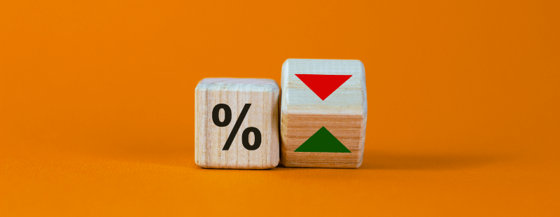 Wooden cubes with a percentage symbol and up/down arrows on an orange background.