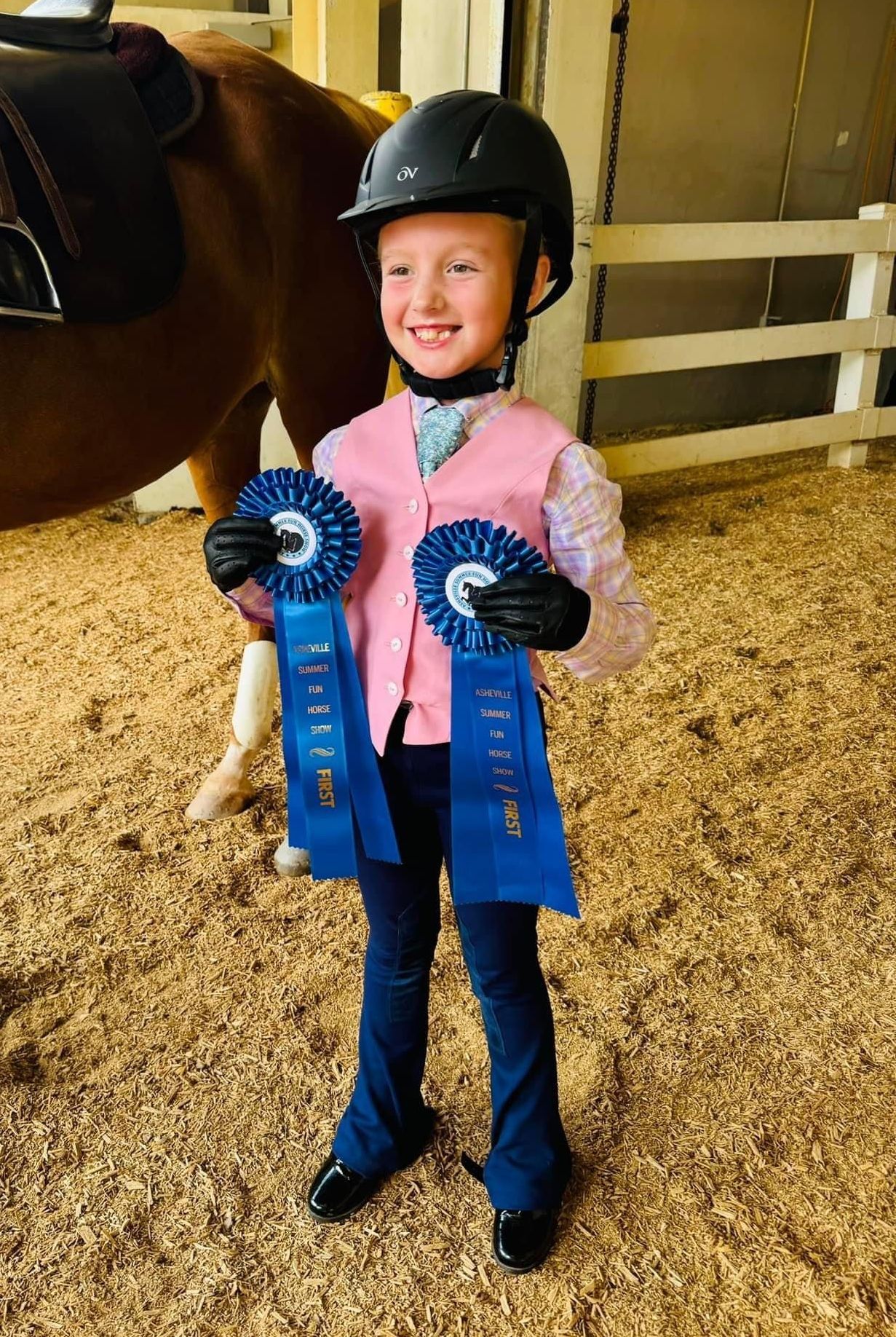 photo of Lenux Stables academy rider holding horse and displaying her winning and reserve ribbons after horse show class