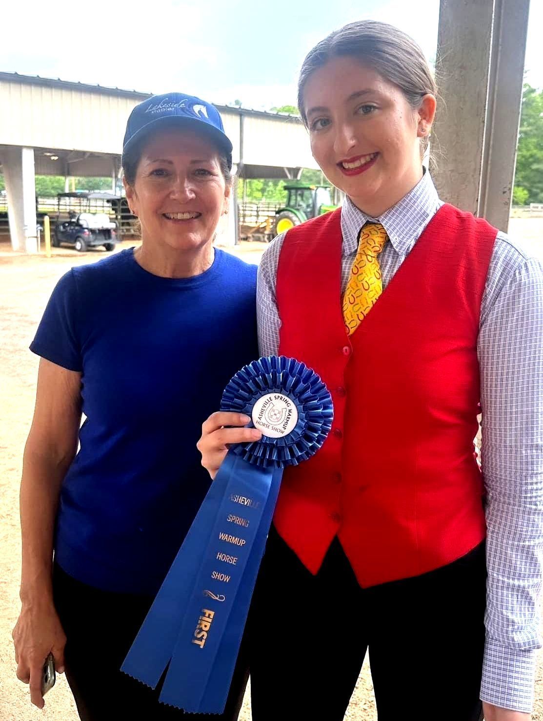 photo of Lenux Stables academy rider holding horse and displaying her ribbons at horse show