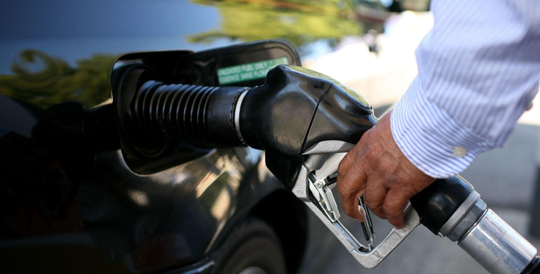A man is pumping gas into a car at a gas station