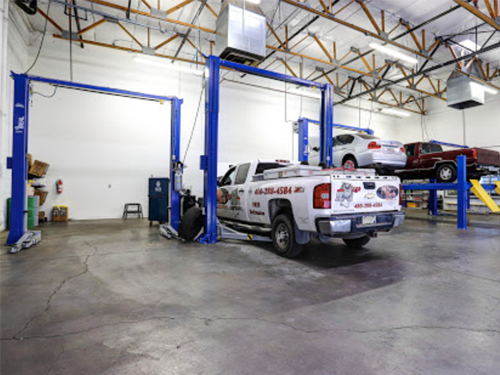 A white truck is on a lift in a garage