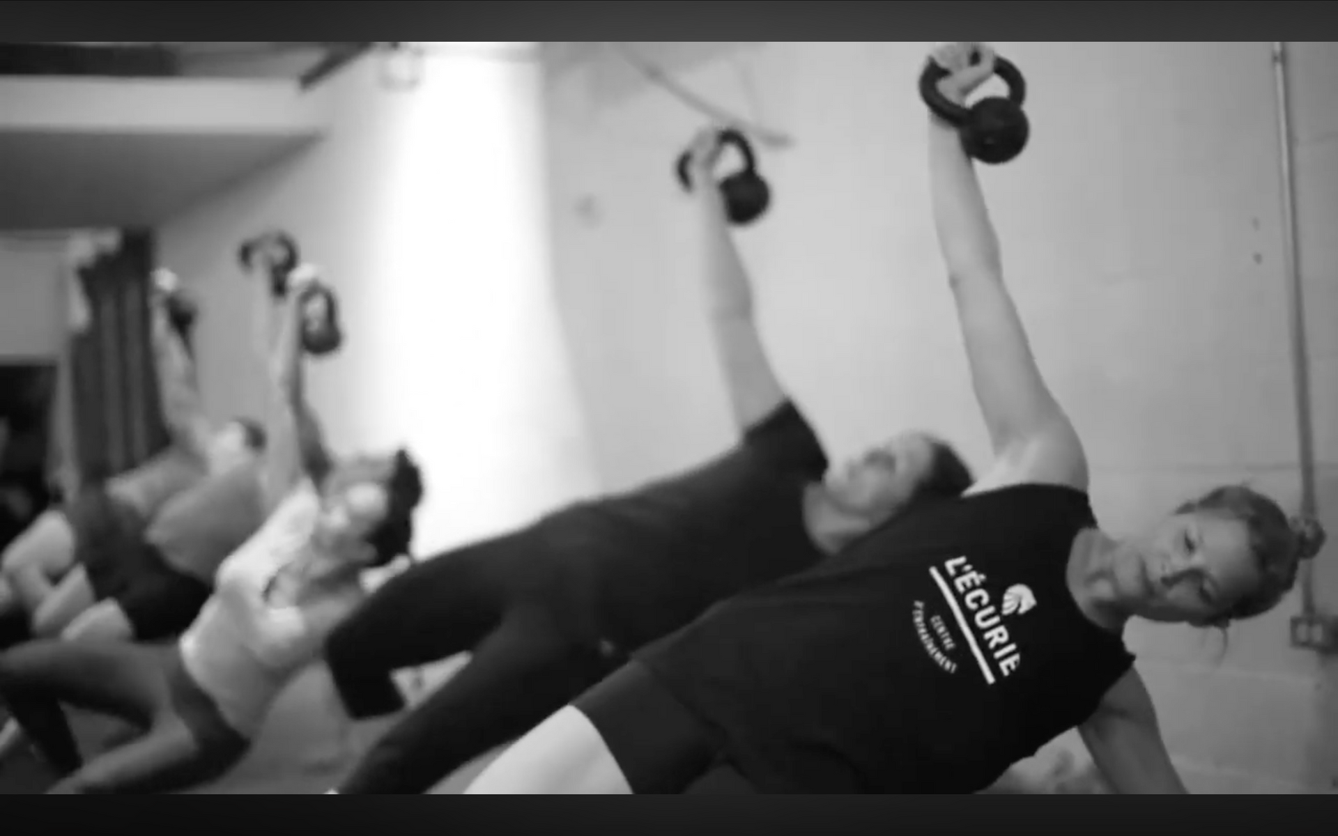 Personne allong&eacute;e faisant un exercice avec des halt&egrave;res, en noir et blanc