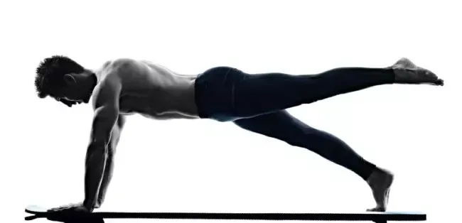 Person en planche sur un bras, une jambe levée, sur un tapis devant un fond blanc