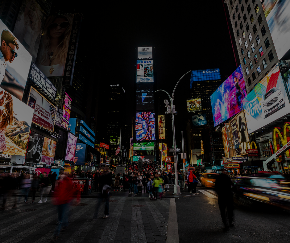 Times Square di notte, con cartelloni pubblicitari luminosi e colorati, le luci brillanti della città e persone che attraversano la strada.