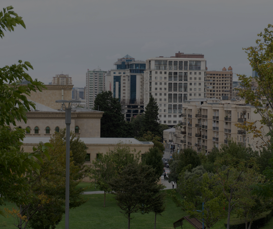 Veduta di un parco cittadino con un monumento centrale, alberi circostanti e diversi palazzi residenziali sullo sfondo.