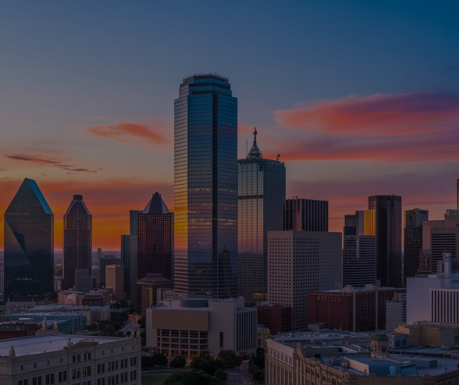 Un tramonto vibrante tinge di arancione lo skyline di Dallas, mettendo in risalto gli imponenti grattacieli contro un cielo azzurro.