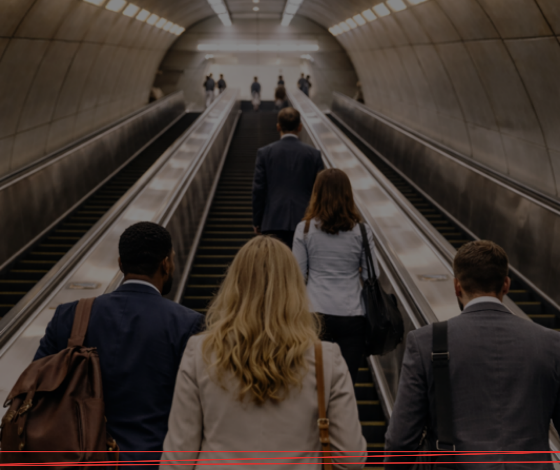 Persone in abiti professionali scendono da una scala mobile in un tunnel della metropolitana.