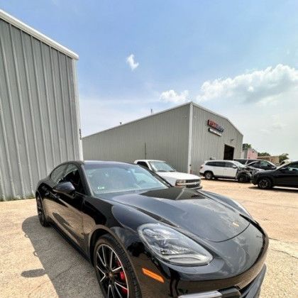 A black porsche panamera is parked in front of a building.
