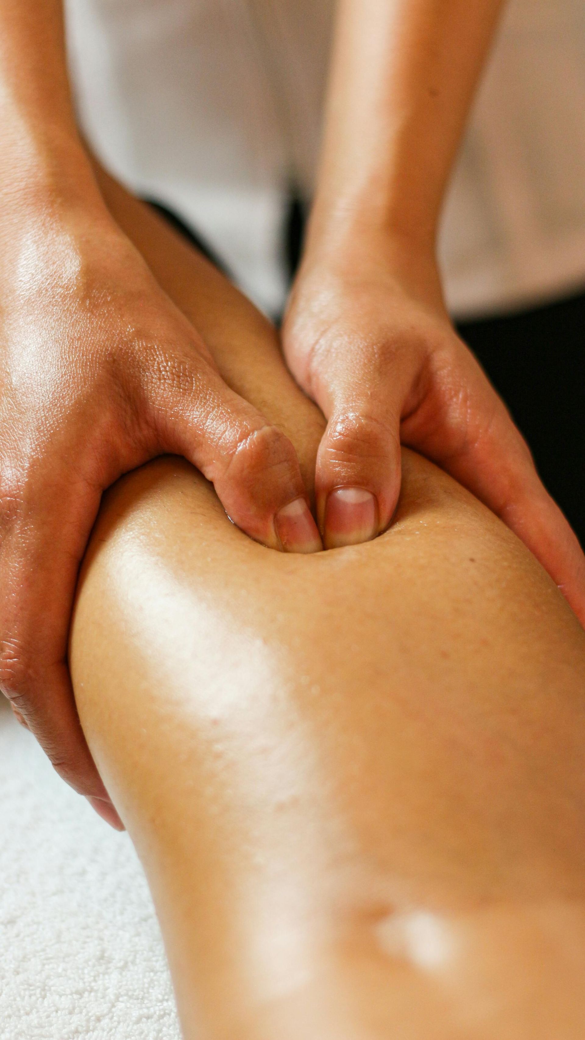 Hands giving a massage to a person’s back with warm oil on skin