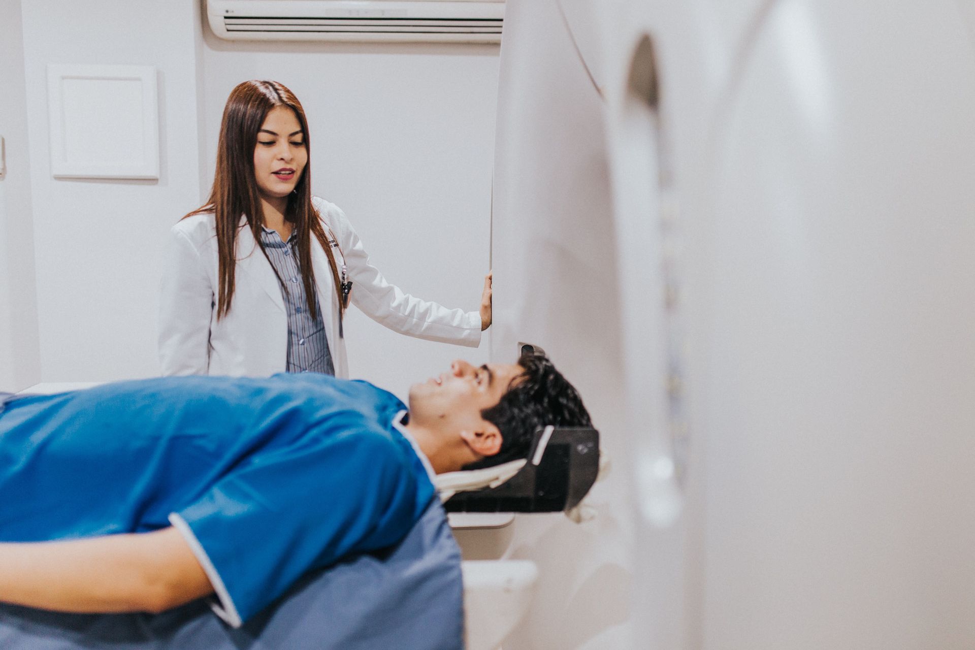 Patient on MRI table while technician stands beside the scanner