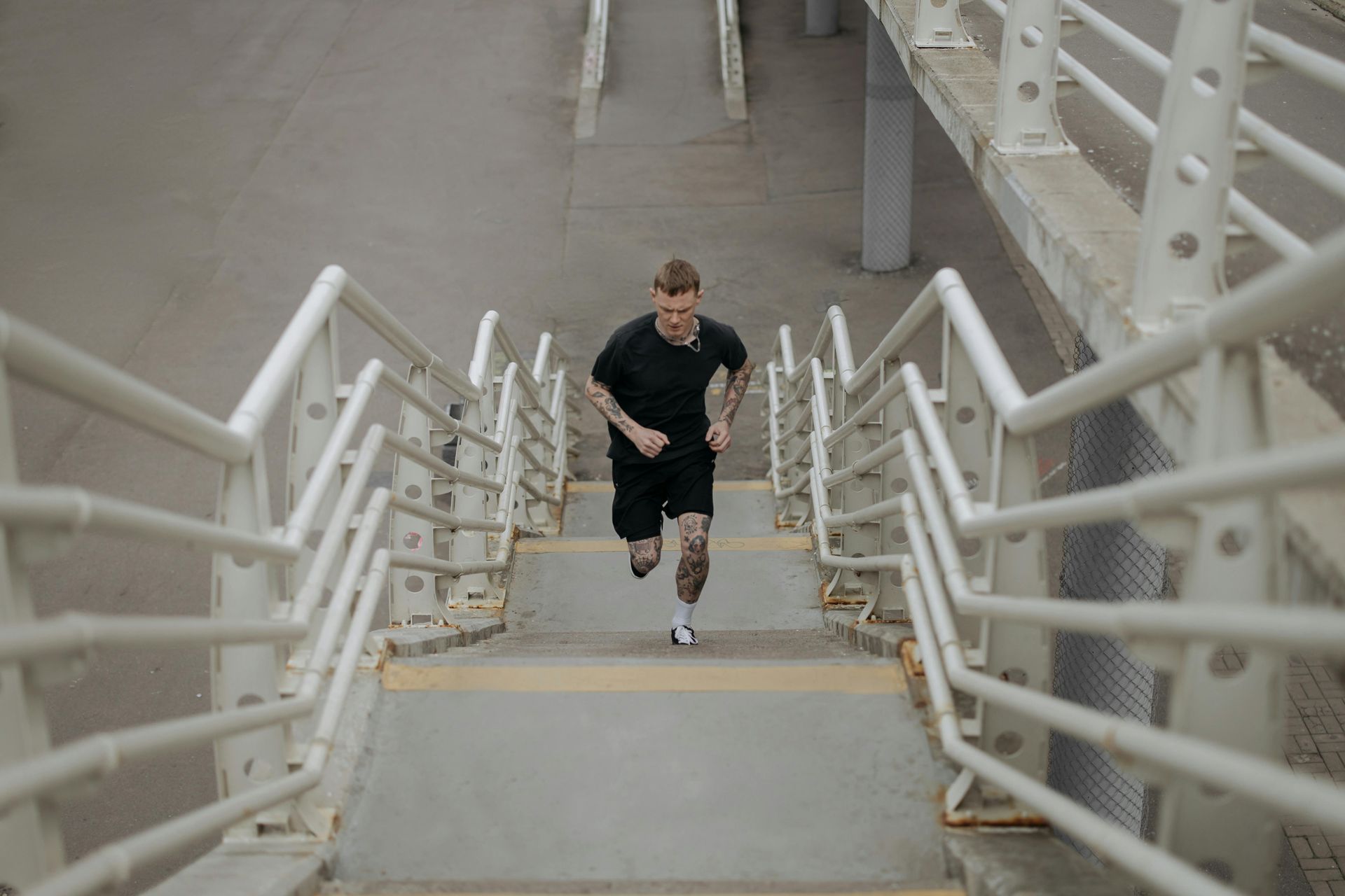 Runner in black and red racing gear runs on a road, casting a long shadow beside a blue line.