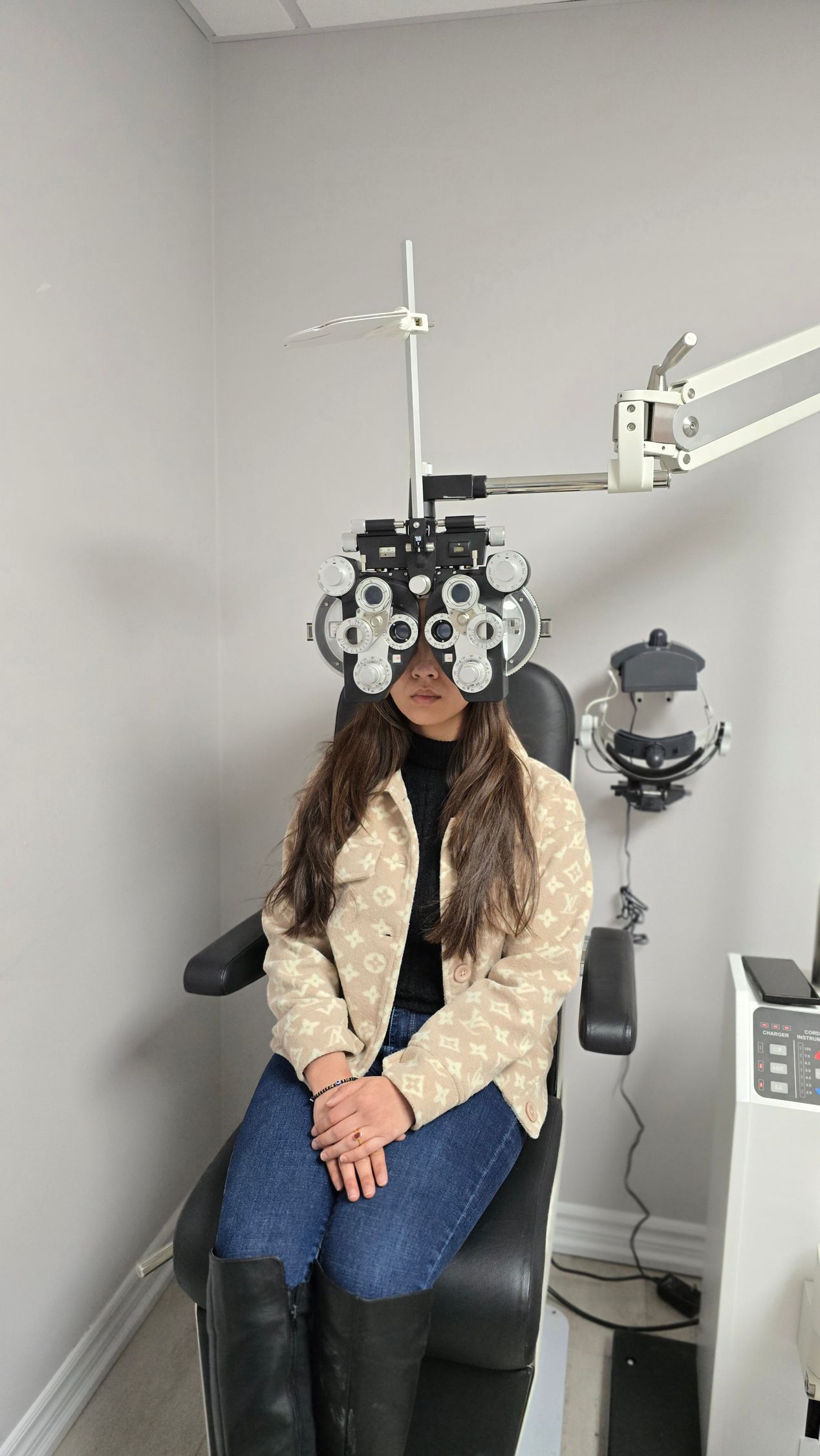 A woman is sitting in a chair getting her eyes checked by an ophthalmologist.