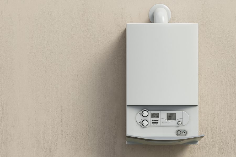 A white gas boiler is mounted to a wall.