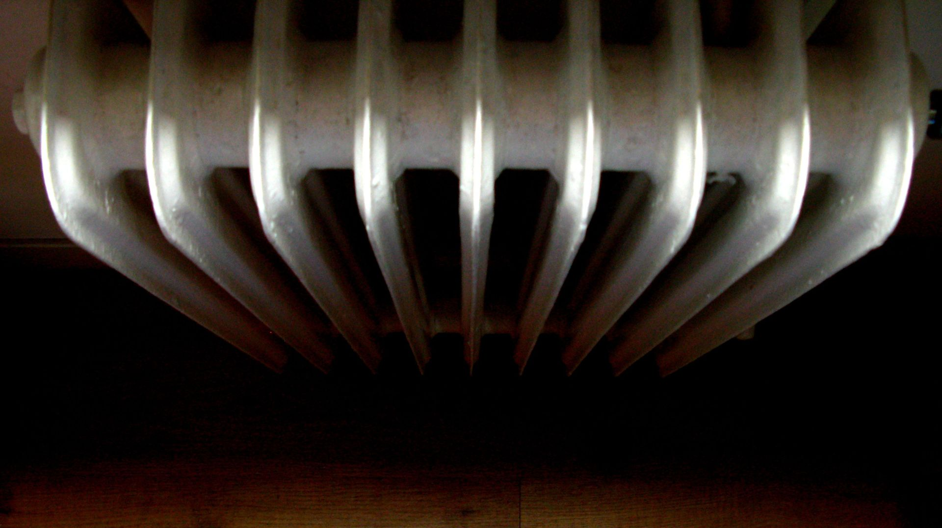 Close-up of metallic curved blades or fins, silver on black background.