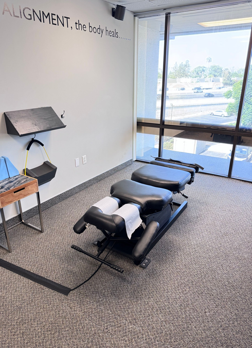 Chiropractic treatment room with adjustment table, lamp, and large window.