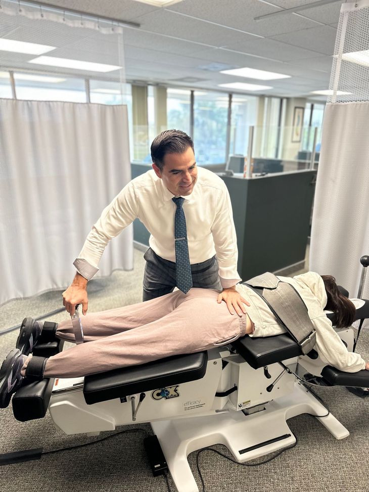 Human spine model in a clinic or classroom, with a blurred person sitting in the background