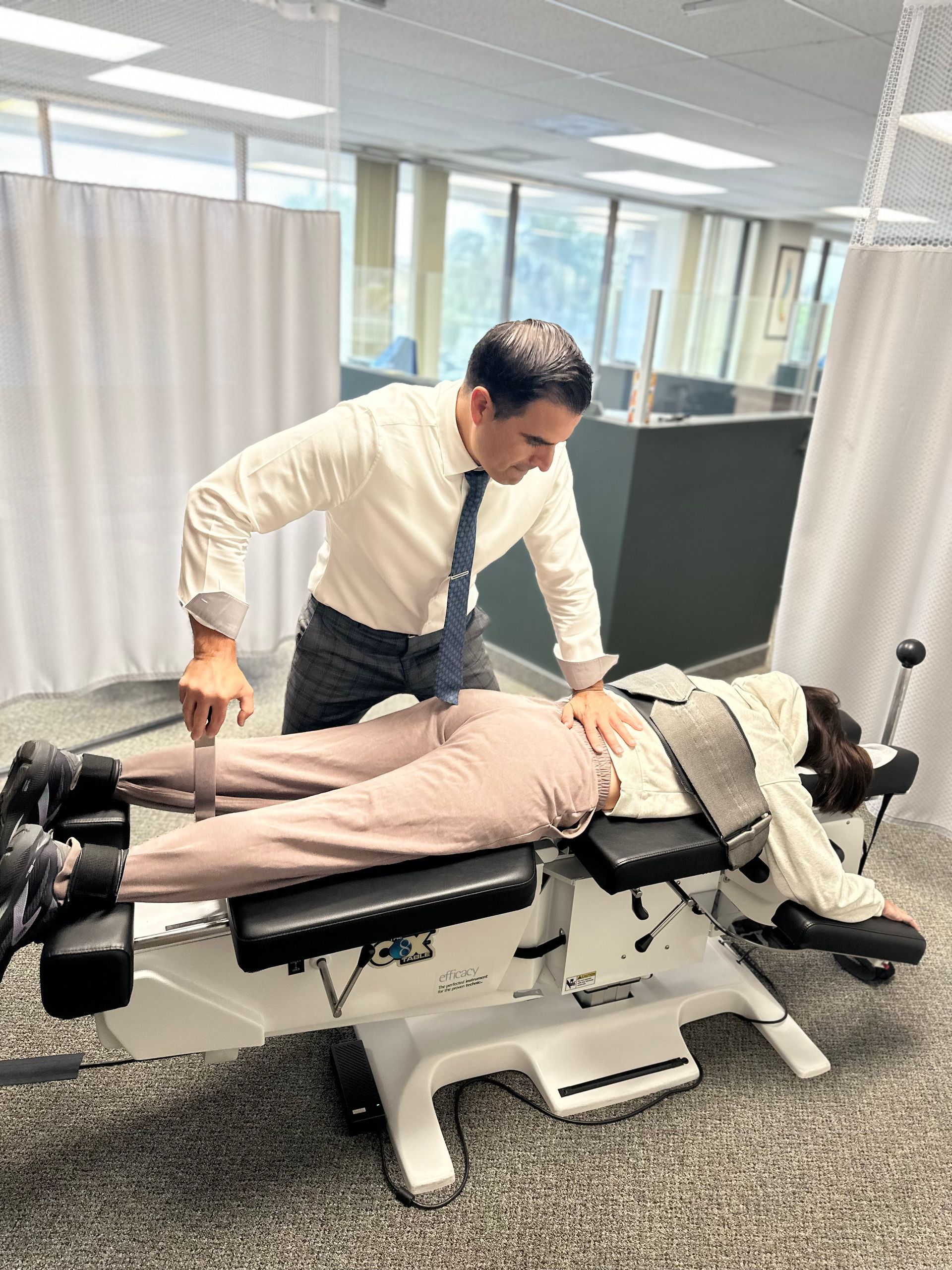 Person adjusting another person on a treatment table in a clinic room