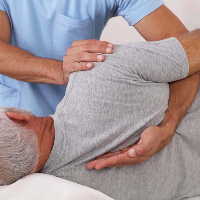 Physical therapist supporting a man lying on his side during a back stretch or adjustment