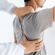Physical therapist examining a patient’s upper back and shoulder