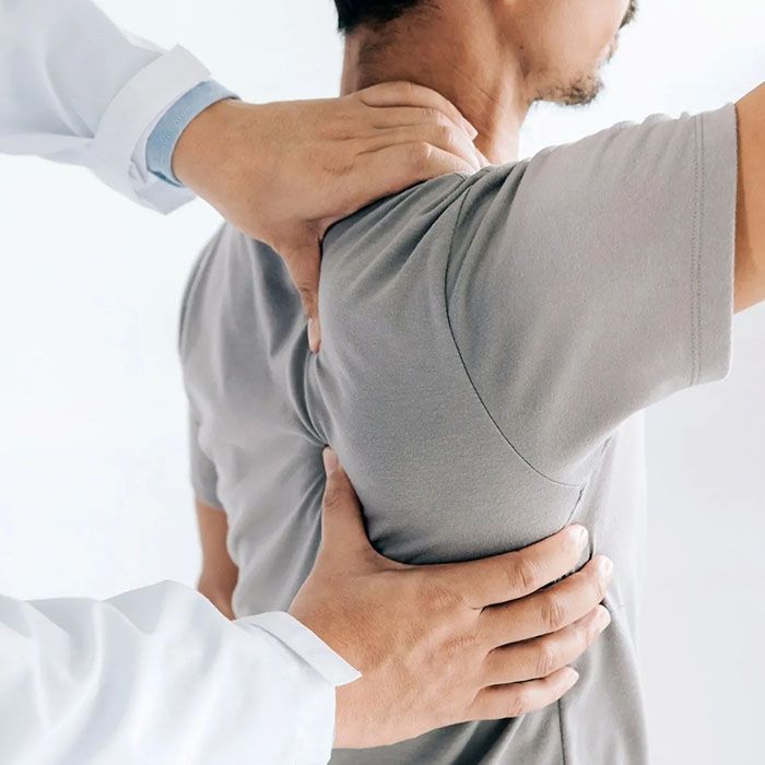 Physical therapist examining a patient’s upper back and shoulder