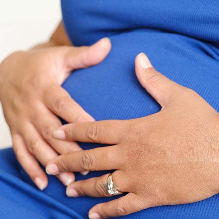 Hands resting on a pregnant belly with a wedding ring visible