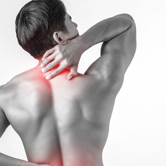 Man holding neck and upper back in pain, with red highlighted area on shoulder and neck