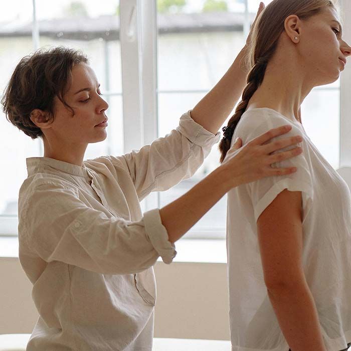 Physical therapist adjusting a woman’s posture in a bright treatment room