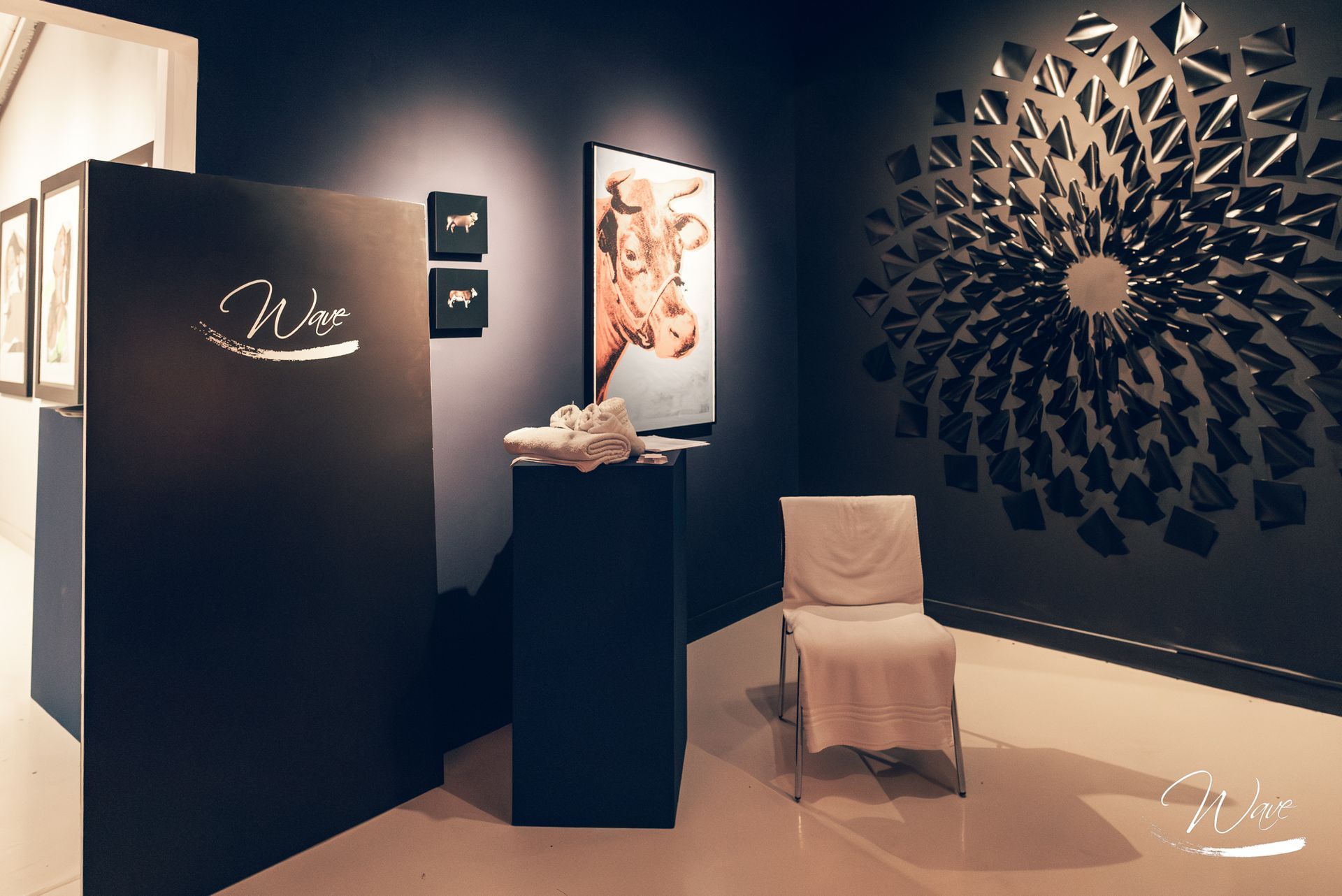 Galleria d'arte con pareti scure, che espone dipinti e sculture.