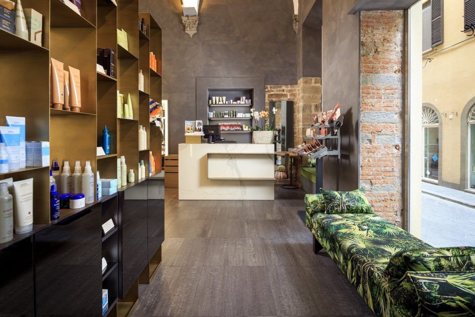 Salon interior with product shelves, reception desk, and a green patterned chaise lounge.