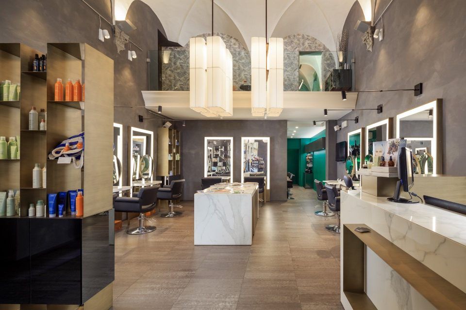 Hair salon interior with large mirrors, styling stations, and central marble island.