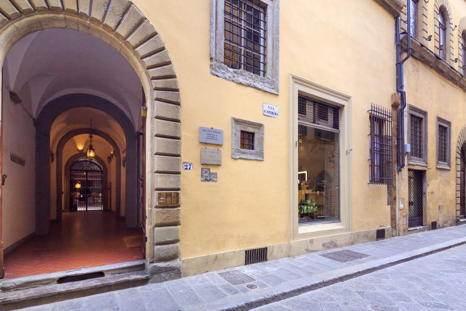 Yellow building with arched entrance and storefront on a cobblestone street in Florence, Italy.