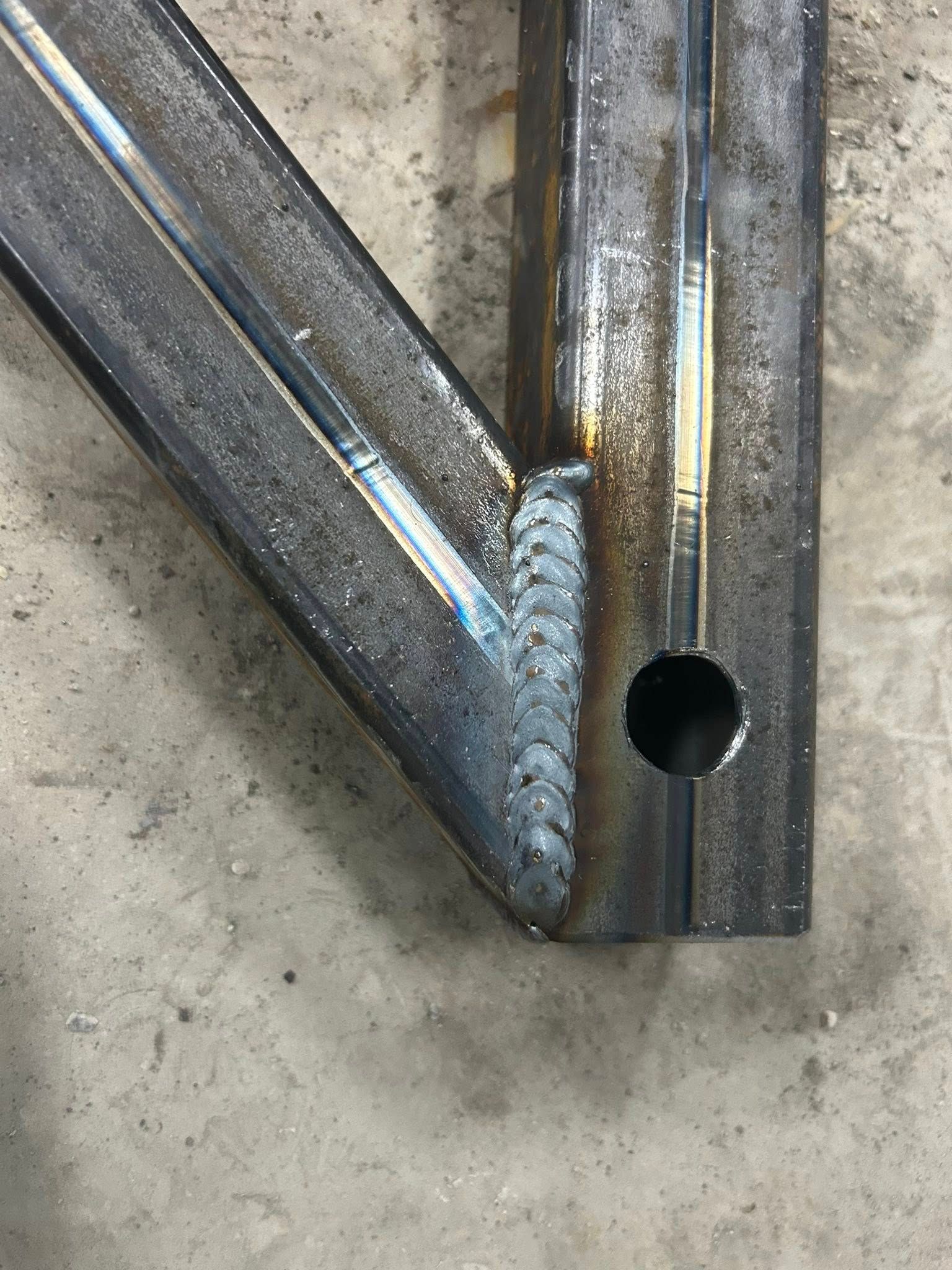 Welded steel frame joint with a drilled hole.