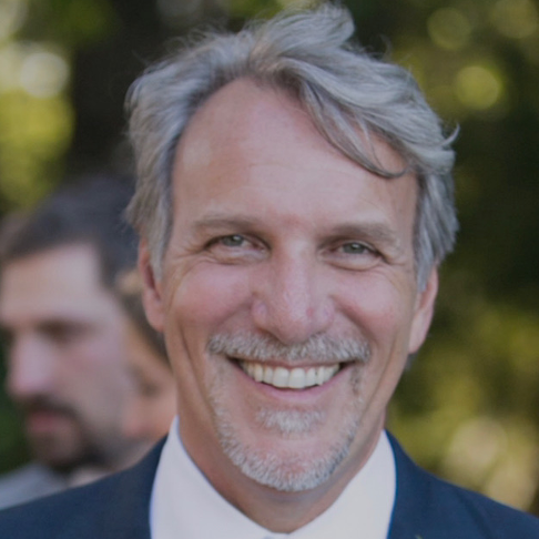 A man in a suit and tie is smiling for the camera.