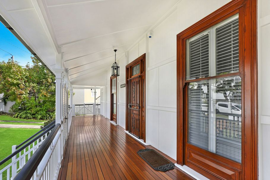 Front porch with wooden floor, white ceiling, and brown-trimmed windows overlooking a green yard