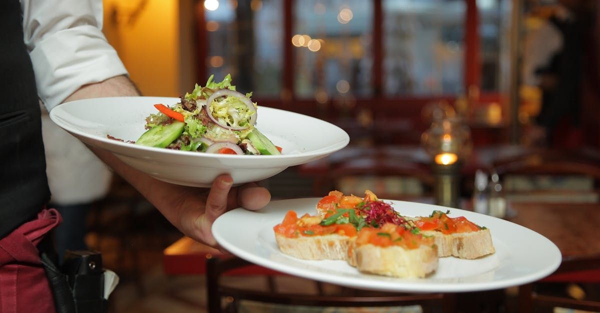 A waiter is carrying two plates of food in a restaurant.