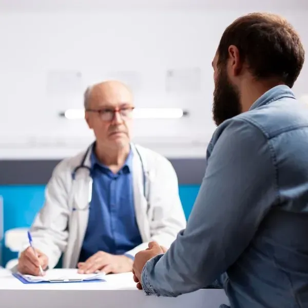 Doctor consulting with a patient across a desk in a bright clinic office