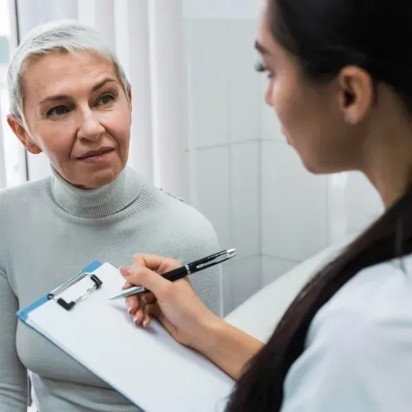 Doctor taking notes while speaking with a patient in a clinic