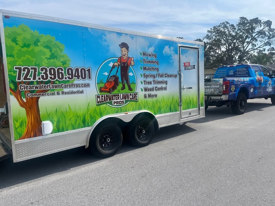 A landscape maintenance trailer and truck parked on a road, featuring the business name, phone number, and listed services.