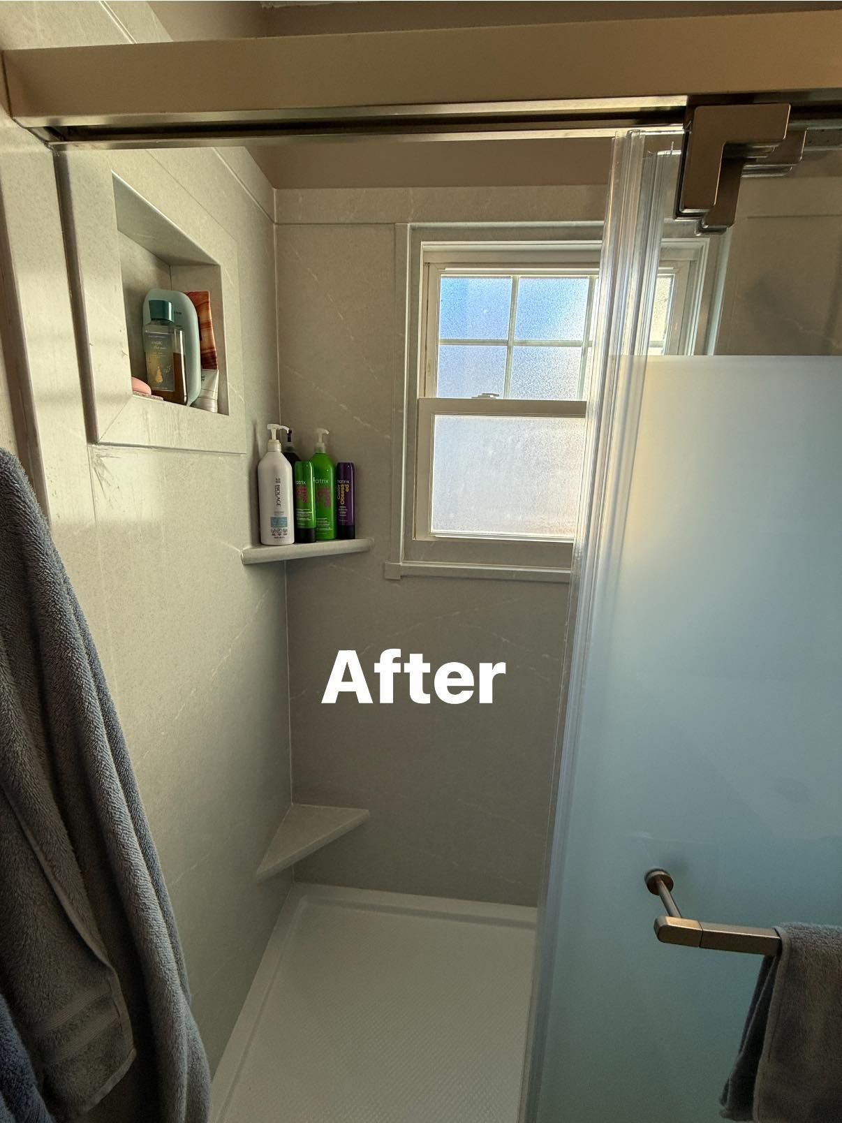 A newly renovated walk-in shower with a built-in recessed shelf, corner shelf, and a frosted window.