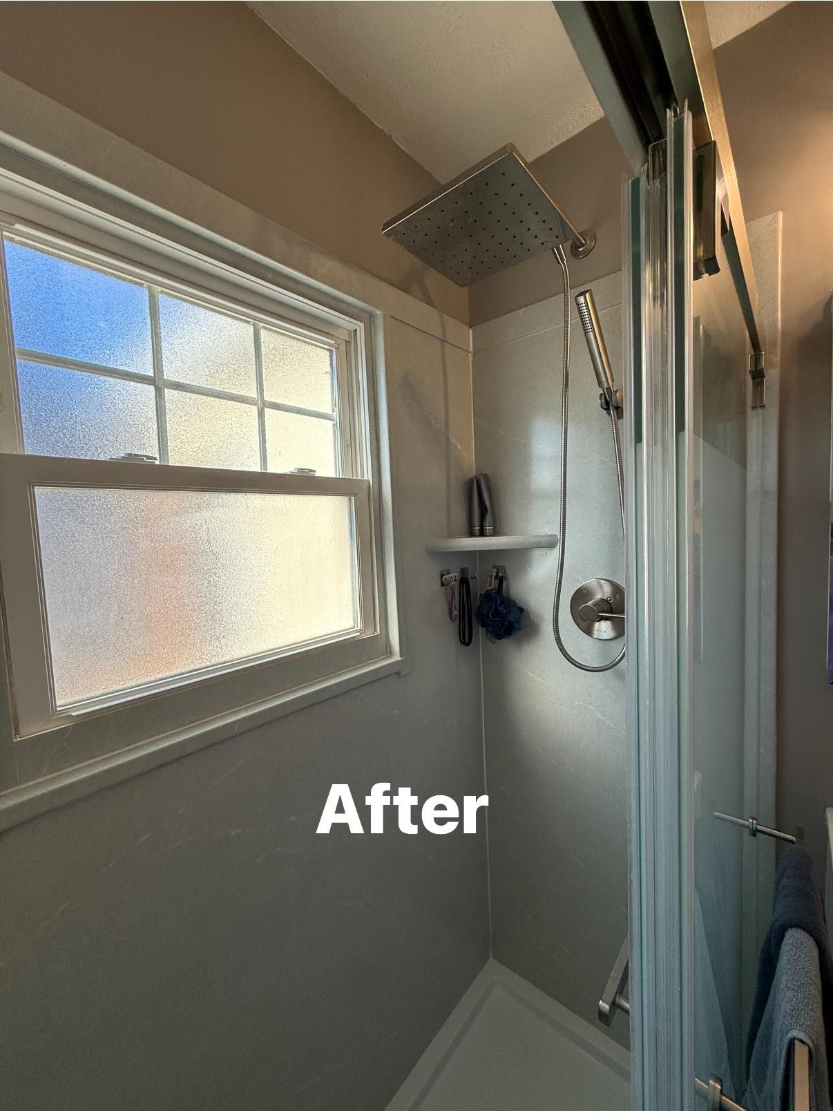 A bathroom shower renovation featuring a new square rainfall showerhead, handheld sprayer, and frosted window.