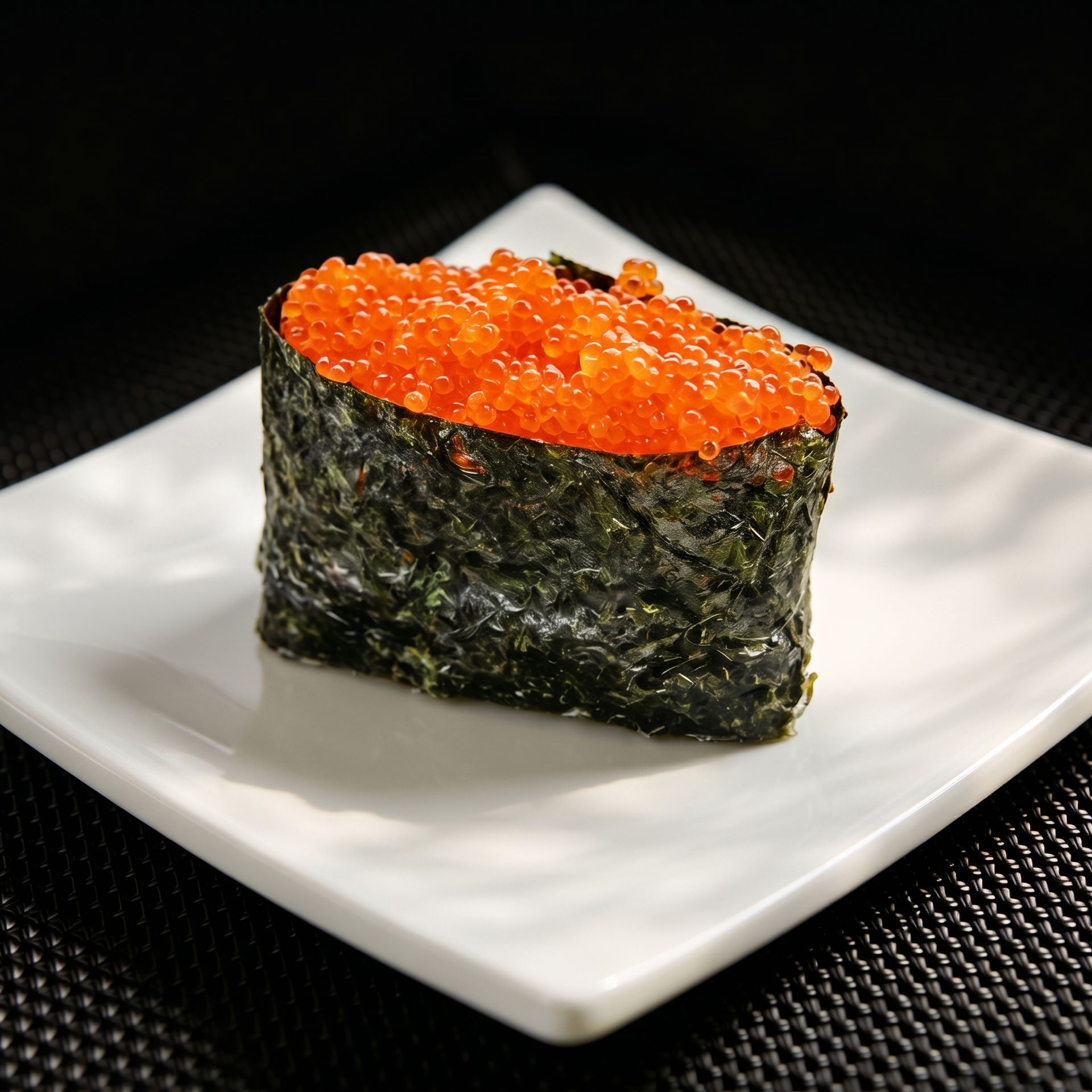 Seafood-topped sushi cube with orange roe on a white plate