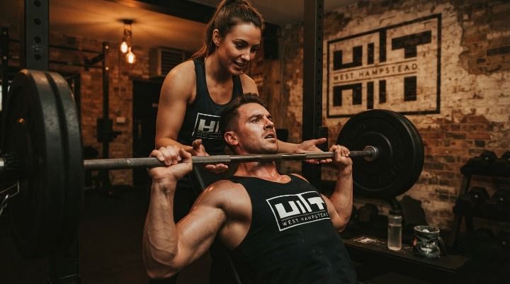Two gym friends training together and encouraging each other during a strength session
