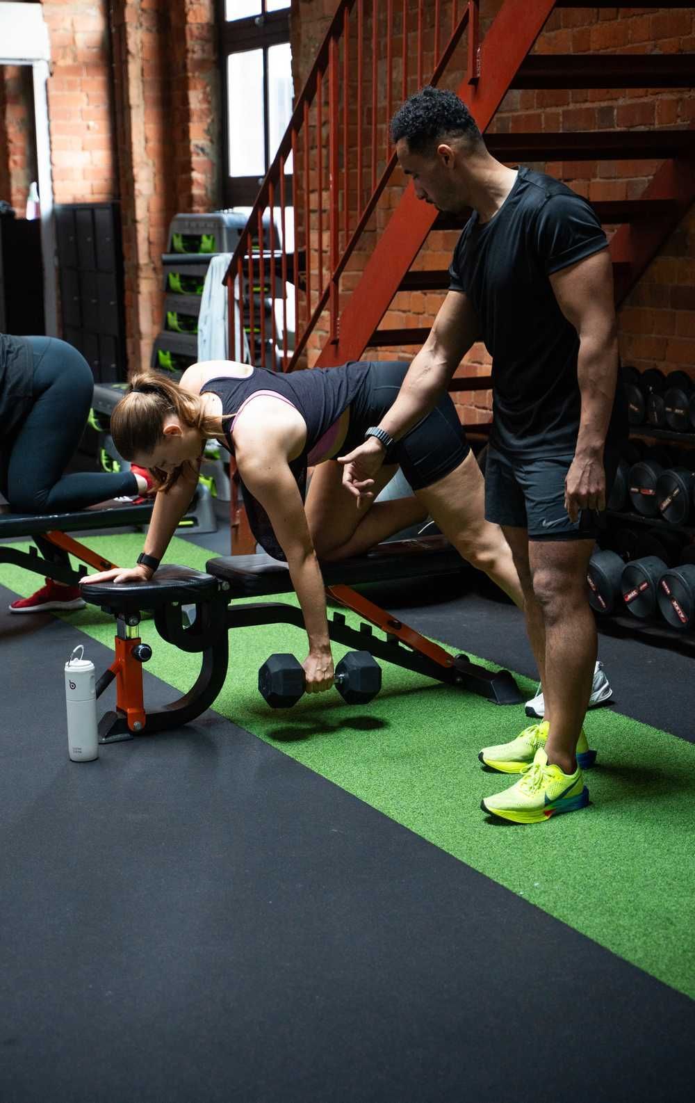 HIIT West Hampstead coach guiding a member through a one-arm dumbbell row